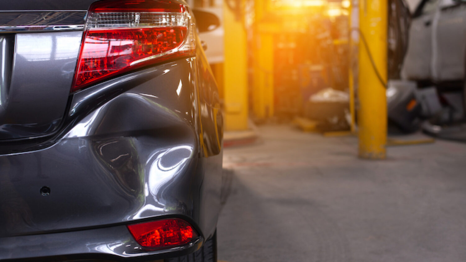 Close up of the rear bumper dent of a grey car in preparation of repair work,Make the surface of the car smooth ,preparing for painting at station service.