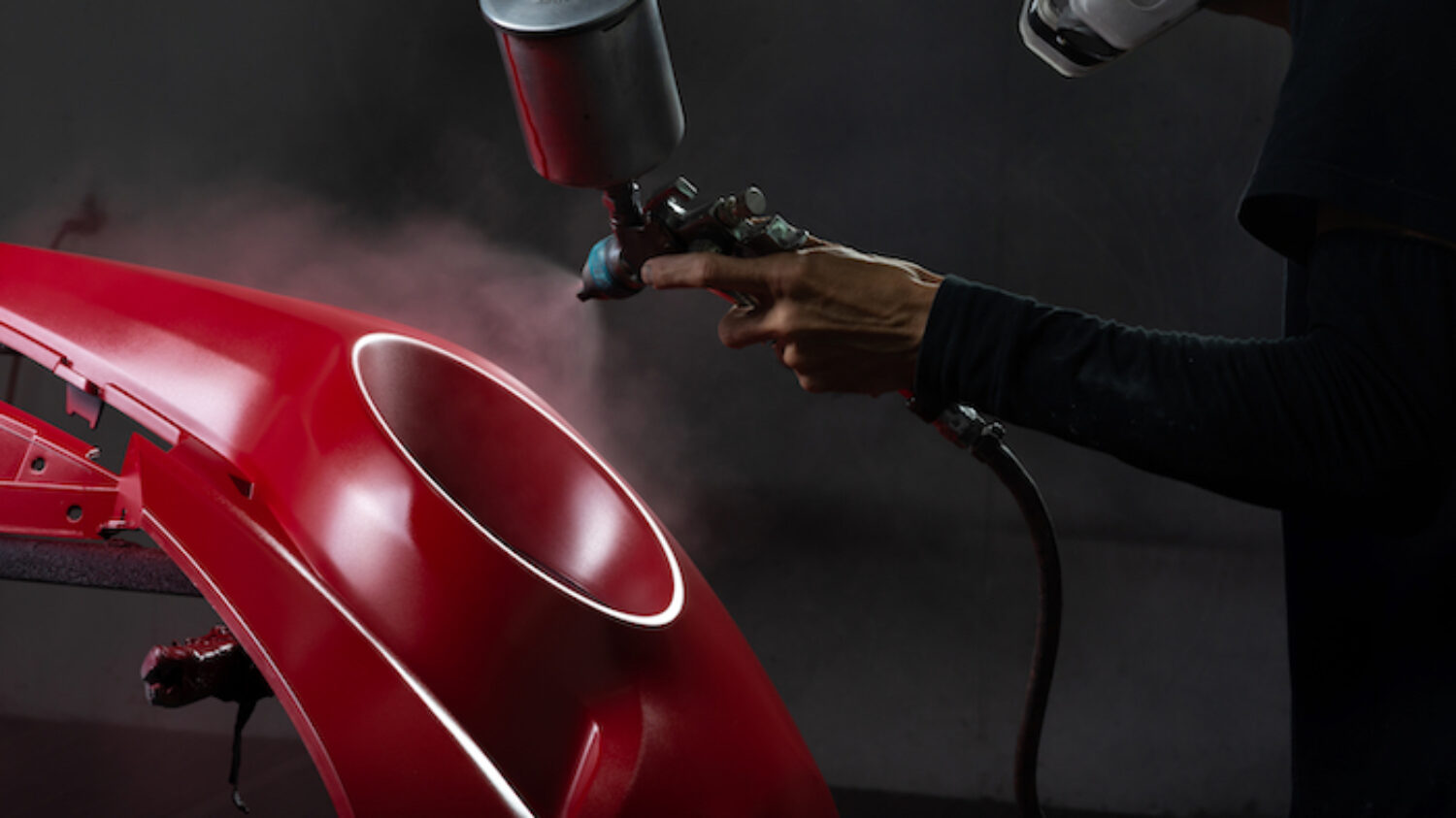 Auto body repair series: Red bumper being painted in paint booth